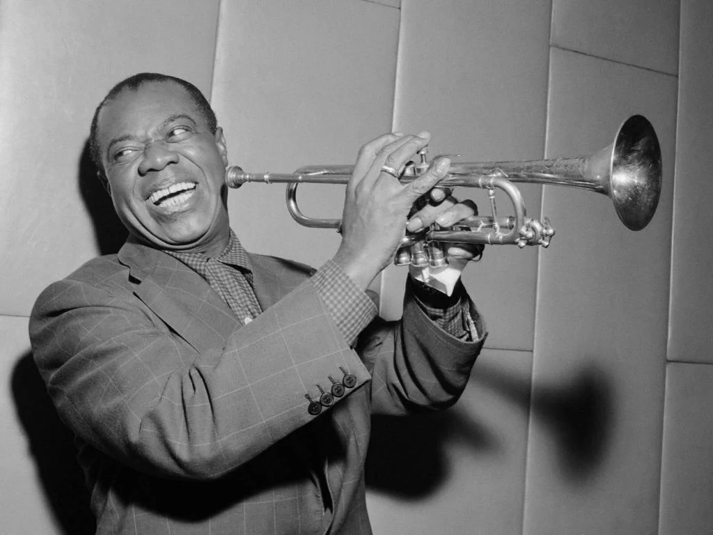 Louis Armstrong 1947 - A man in a blue suit playing a trumpet