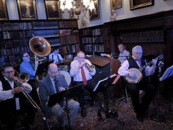 The John Gill Jazz Band: L-R: Jim Fryer (tmbn), Brian Nalepka (bs), Dan Block (cl), Kevin Dorn (dr), Simon Wettenhall (tmpt) Conal Fowkes (p) and John (bnj,voc, bandleader) in the Library
